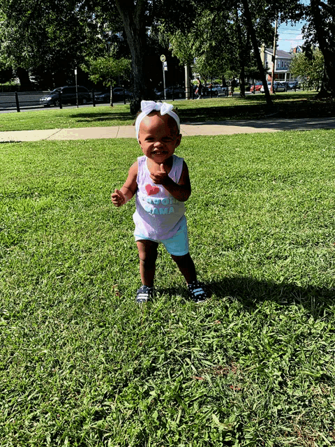 a little girl wearing a shirt that says i love mama stands in the grass