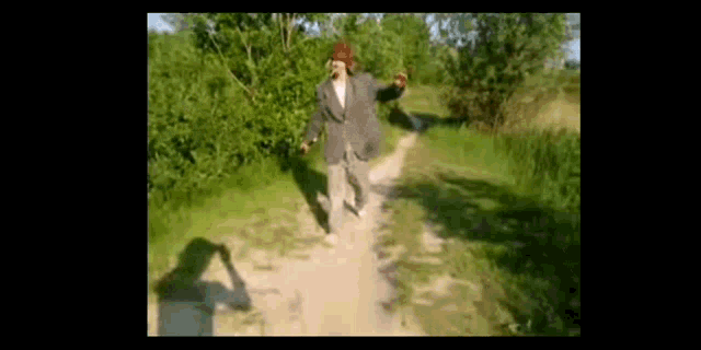 a man in a hat is walking down a dirt road