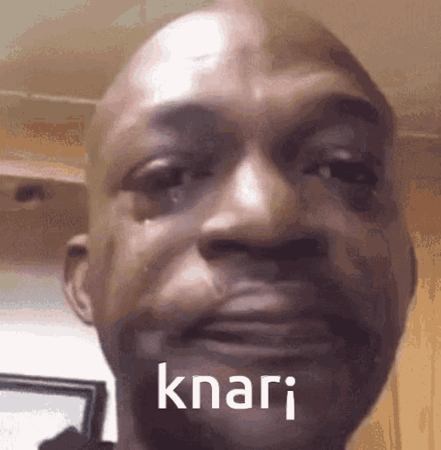 a close up of a man 's face with a tear coming out of his eye and the word knari written on it .