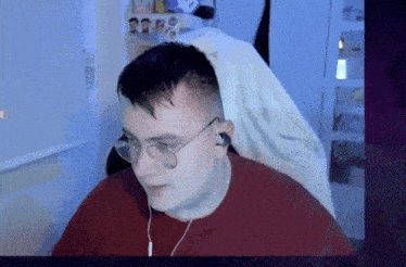 a man wearing glasses and earbuds is sitting in front of a computer screen