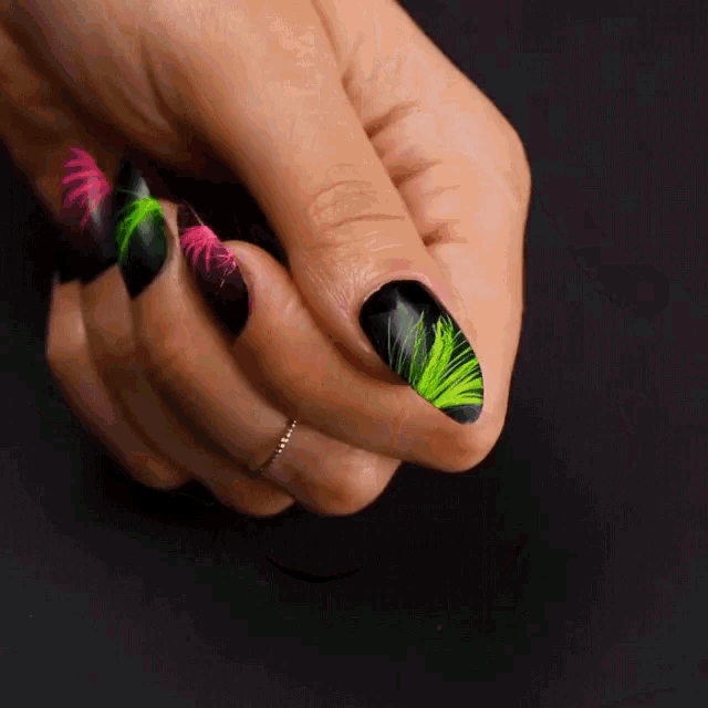 a close up of a woman 's hand with neon green and pink nails