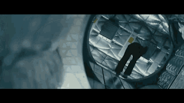 a man is walking through a tunnel with a yellow sign that says ' emergency exit ' on it