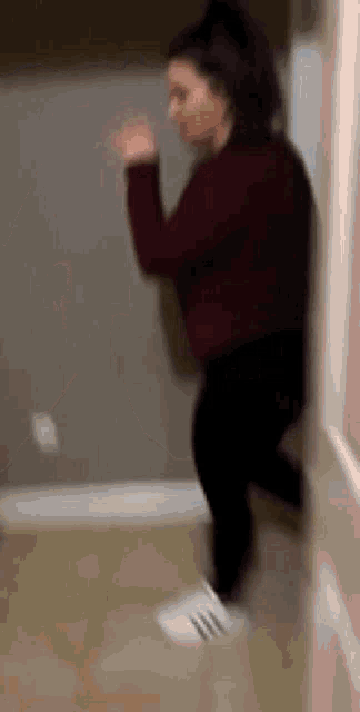 a woman in a red sweater and black pants is dancing in a room .