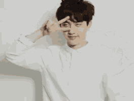 a young man is making a peace sign with his hands .