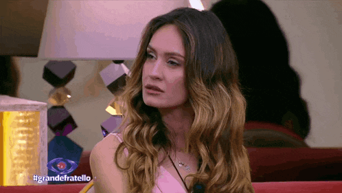 a woman sitting in front of a lamp with the hashtag grandefratello on the screen