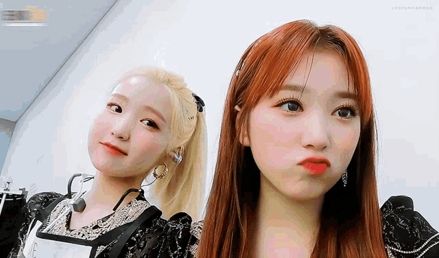two girls are posing for a picture and one of them is wearing a microphone around her neck