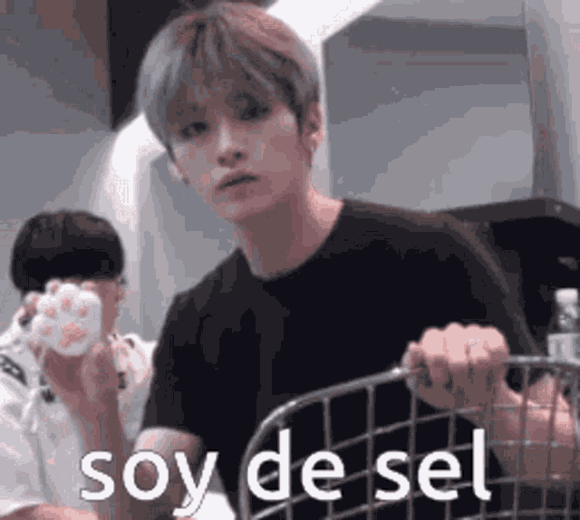 a young man in a black shirt is holding a cat paw and saying `` soy de sel '' .