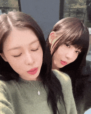 two girls are posing for a picture and one is wearing a necklace