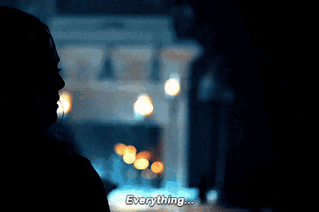 a woman in a dark room says everything in front of a blurry background