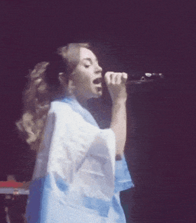a woman singing into a microphone while holding a blue and white flag