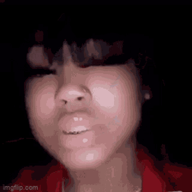 a close up of a woman 's face with a red shirt and a black hat .