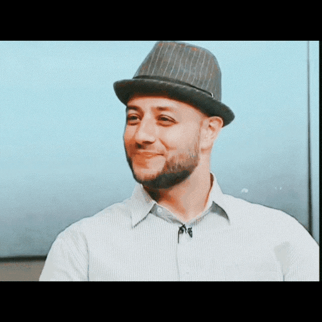 a man with a beard wearing a hat and a striped shirt