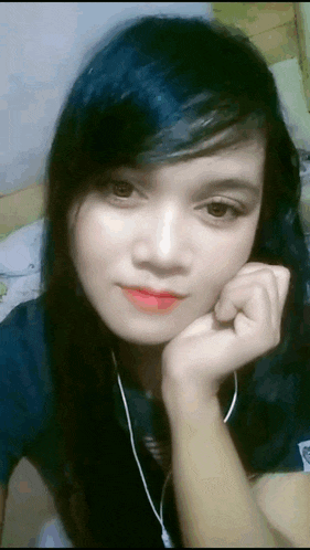 a girl with long black hair and red lipstick looks at the camera with her hand on her chin