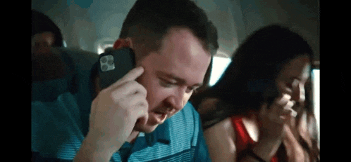 a man is talking on a cell phone while sitting on an airplane