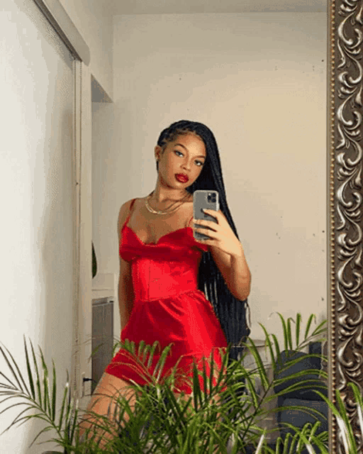 a woman in a red dress is taking a picture of herself in the mirror