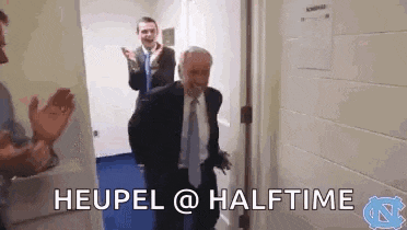 a man in a suit and tie is walking through a doorway while people applaud .