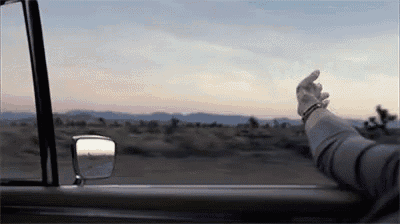 a person is sticking their hand out of a car window .