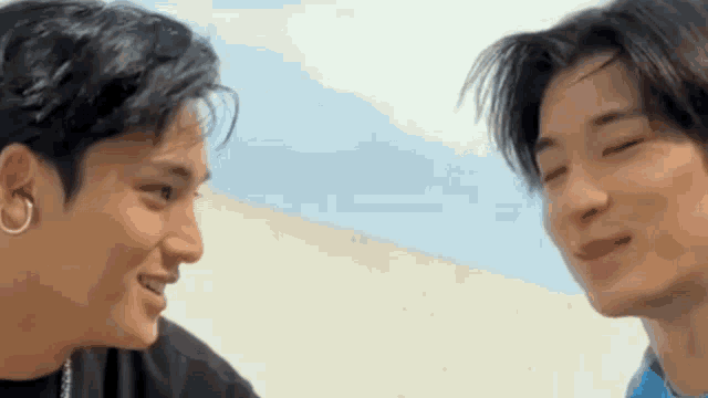 two young men are standing next to each other and looking at each other with their eyes closed .