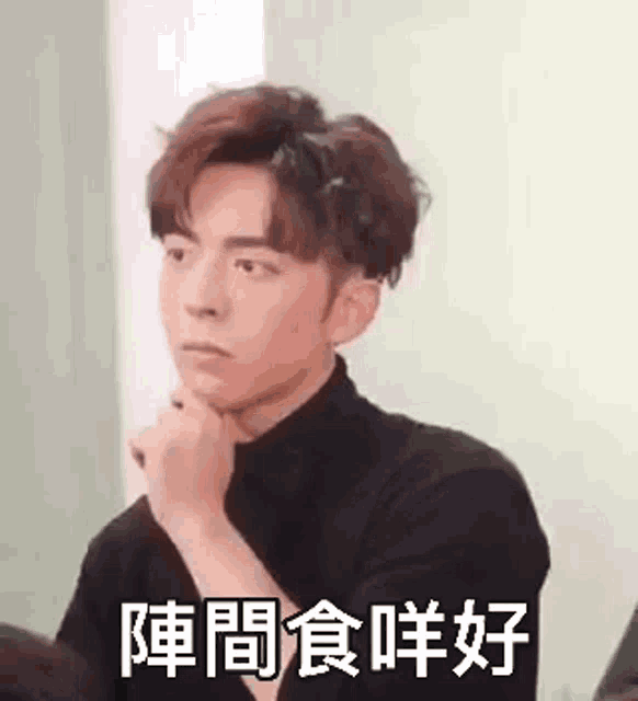 a young man in a black turtleneck is making a funny face .