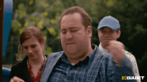 a man in a plaid shirt is sitting in front of a woman and a man in a blue hat