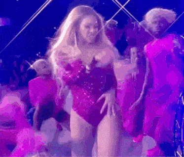 a woman in a pink bodysuit is dancing on a stage .