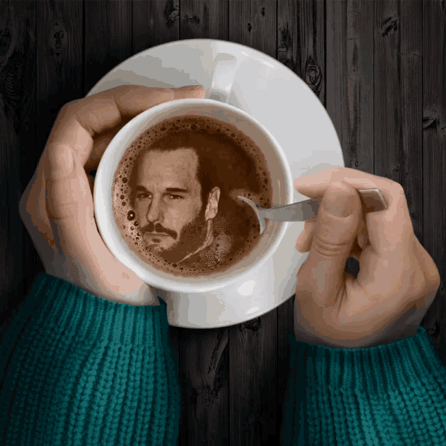 a person is holding a cup of coffee with a picture of a man in the coffee