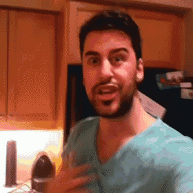 a man with a beard is wearing a scrub top and making a funny face .