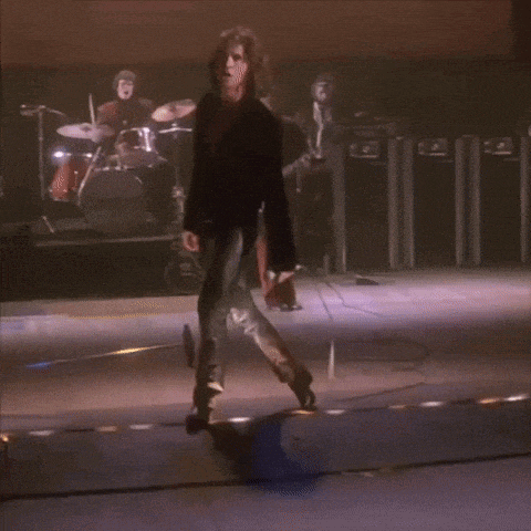 a man with curly hair is walking on a stage