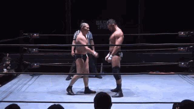 two men in a wrestling ring with a referee and a sign that says glory