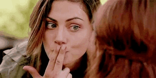 a woman is covering her mouth with her finger while another woman looks at her .