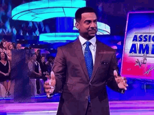 a man in a suit and tie is standing on a stage in front of a sign that says assic am .