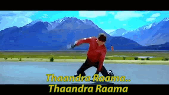 a man in a red shirt is kneeling down in front of mountains