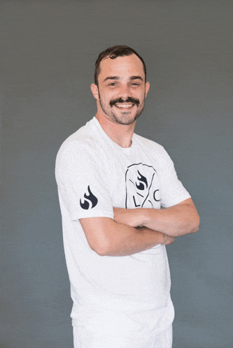 a man with his arms crossed wears a white shirt with a picture of a ghost on it