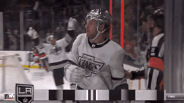 a hockey player wearing a kings jersey stands in front of a referee