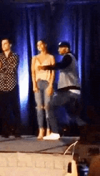 a man is standing on a stage holding a woman 's hand .