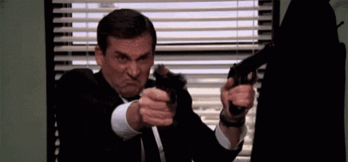 a man in a suit and tie is pointing a gun at another man .