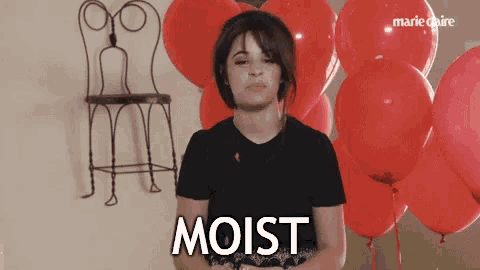a woman is standing in front of red balloons and says moist