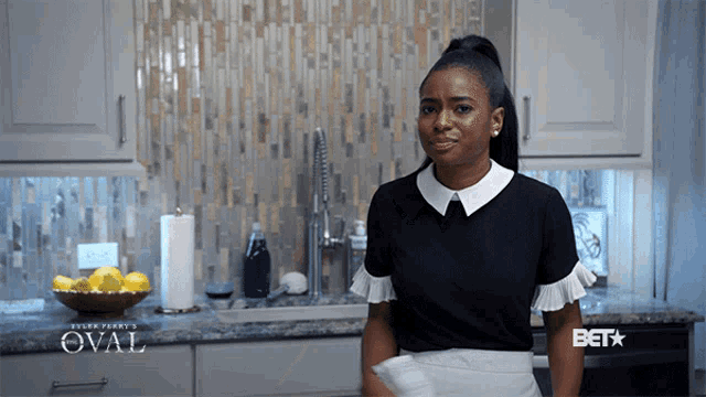 a woman standing in a kitchen with a bet logo on the counter