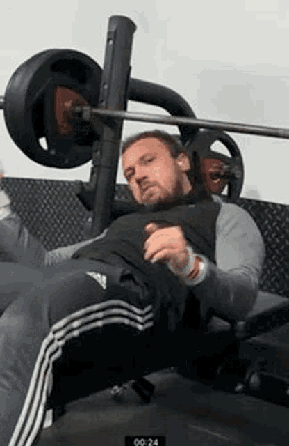 a man is laying on a bench with a barbell on it .