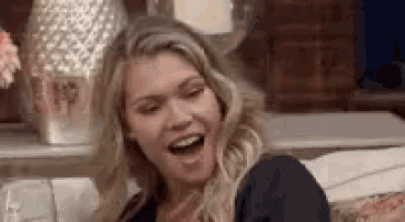 a woman is sitting on a couch laughing and smiling .