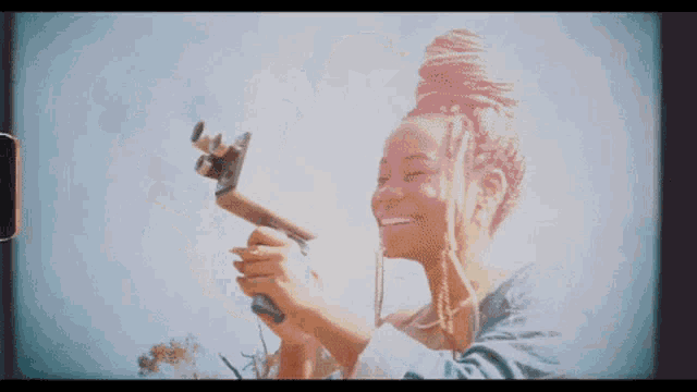 a woman is smiling while holding a camera in her hands