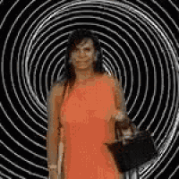 a woman in a red dress is standing in front of a spiral .