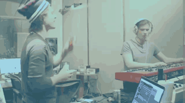 a man wearing headphones is playing a keyboard next to a laptop