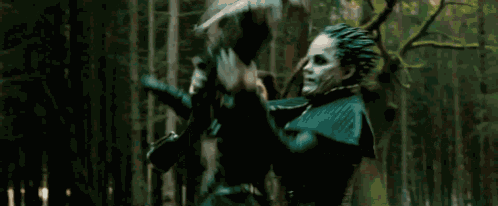 a man is running through a forest with a gun .