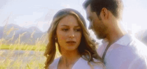 a man and a woman are standing in a field of tall grass .