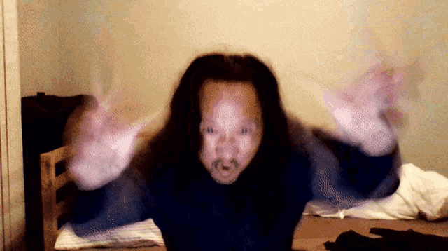 a man with long hair and a mustache is making a funny face with his arms outstretched