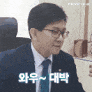 a man in a suit and tie is sitting in a chair and making a face .