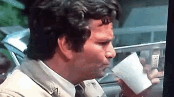 a man in a trench coat drinks from a white cup
