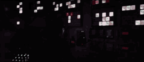 a man in a mask is standing in a dark room with a glass wall behind him .
