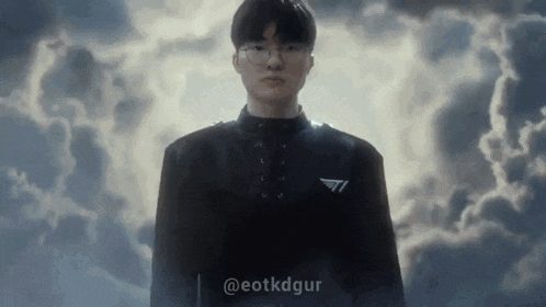a man wearing glasses and a black jacket is standing in front of a cloudy sky .